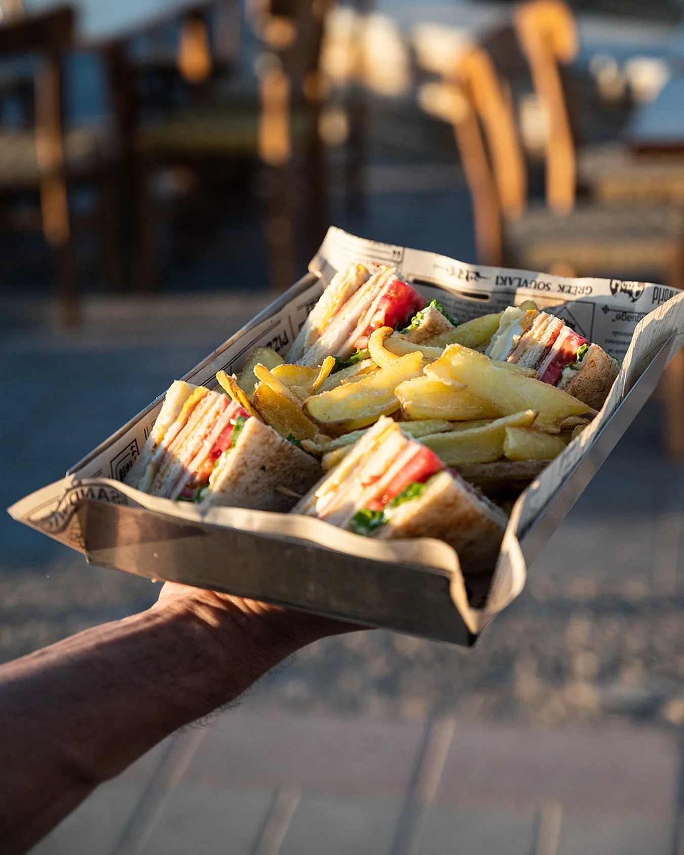 Club sandwich with fries served in newspaper-style paper